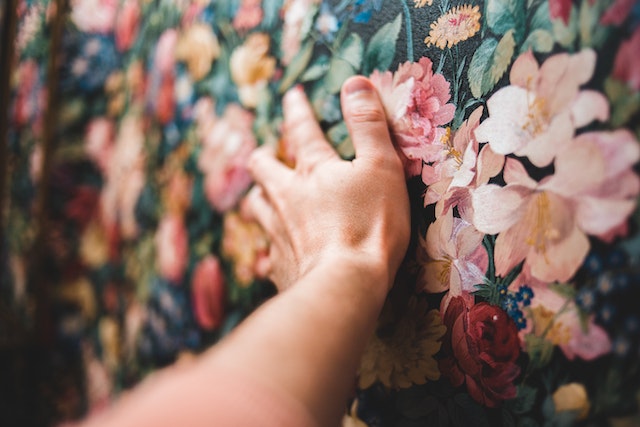 Crop person touching colourful floral wallpaper

