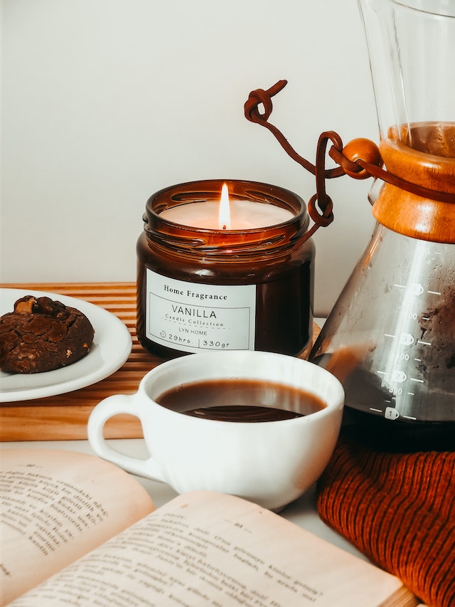 Black Coffee Beside a Lighted Scented Candle