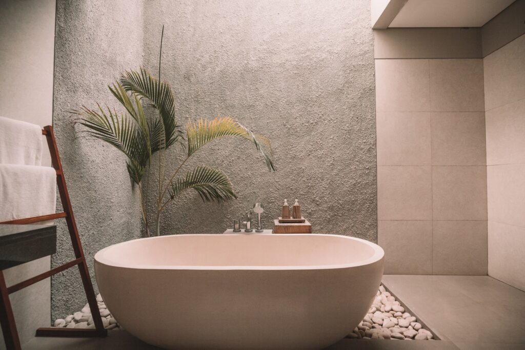 a white ceramic bathtub beside a plant