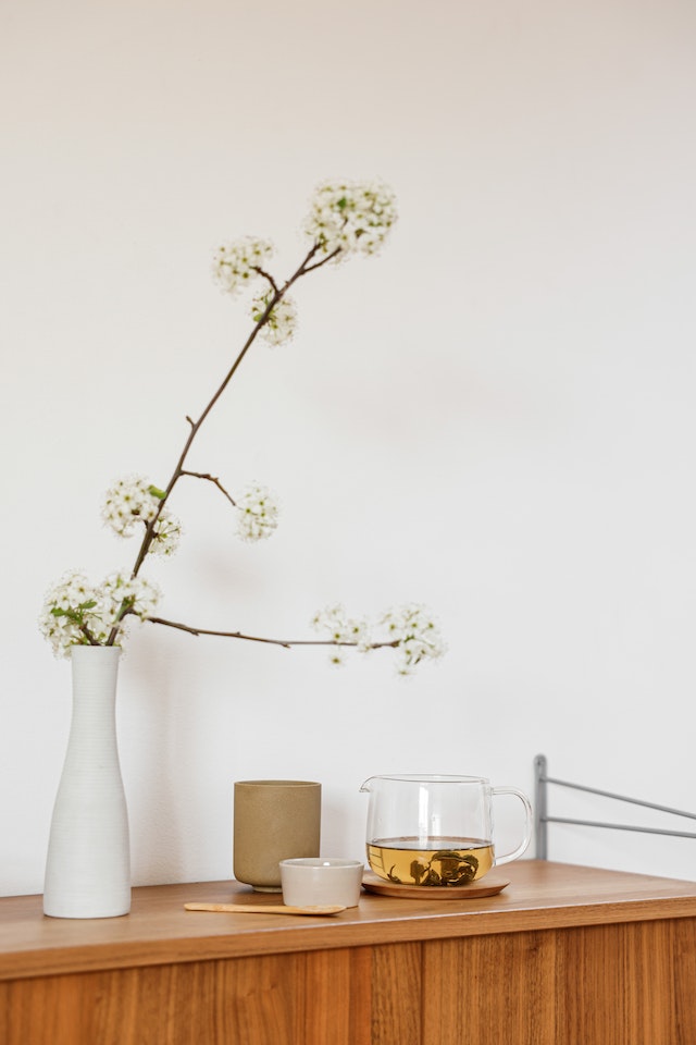 Still Life with a Fruit Tree Branch with White Flowers and Tea on Cupboard
